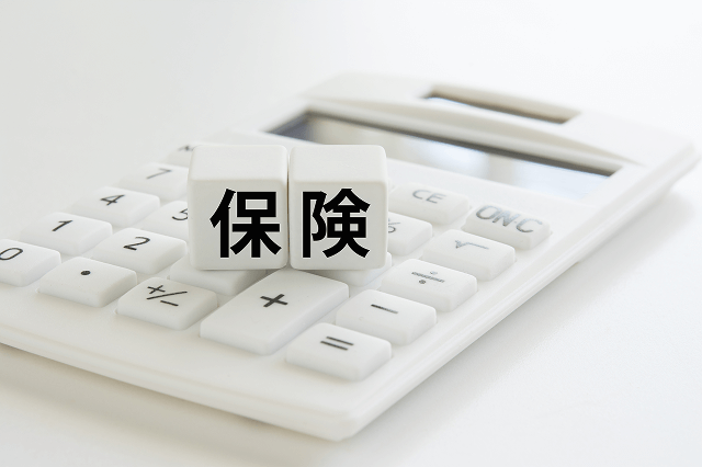 電卓の上に置かれた保険と書かれたブロック
